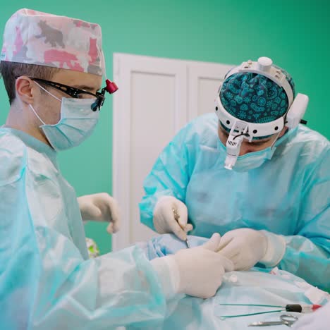 professional doctors during operation. male surgeons with surgical tools operate the patient. medical specialists with flashlights on head in the operating room.