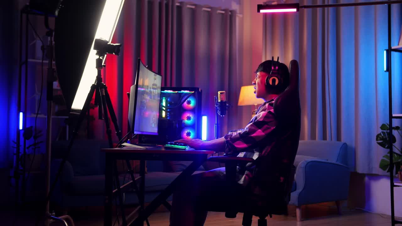 Side View Of Asian Boy Streamer Having A Backache While Playing Game Over Network On Personal Computer. Live Stream Video Game, Desk Illuminated By Rgb Led Strip Light