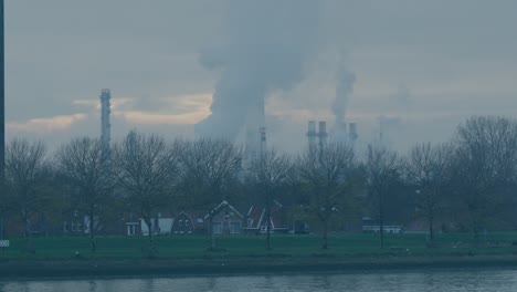 a suburb in rotterdam with an industrial area in the background where smoke is billowing from towers