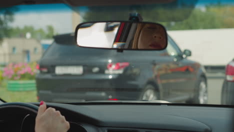 Woman-in-hurry-looks-in-car-mirror-and-windows-to-check-road