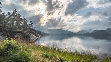 sun rays pierce through the stormy clouds whirling over the lake and a forest in a timelapse video