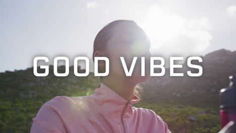 animation of the words good vibes written in white over woman exercising in mountains drinking water