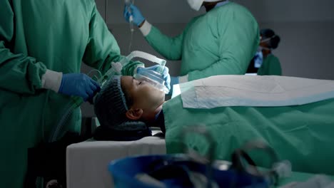 diversos cirujanos con máscaras faciales usando máscara de oxígeno en el paciente en la sala de operaciones en cámara lenta