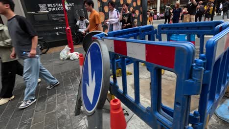 people walking around construction barriers in busy street