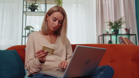 Young-woman-using-credit-bank-card-and-laptop,-transferring-money,-purchases-online-shopping