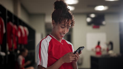 a soccer player in a locker room using a cell phone