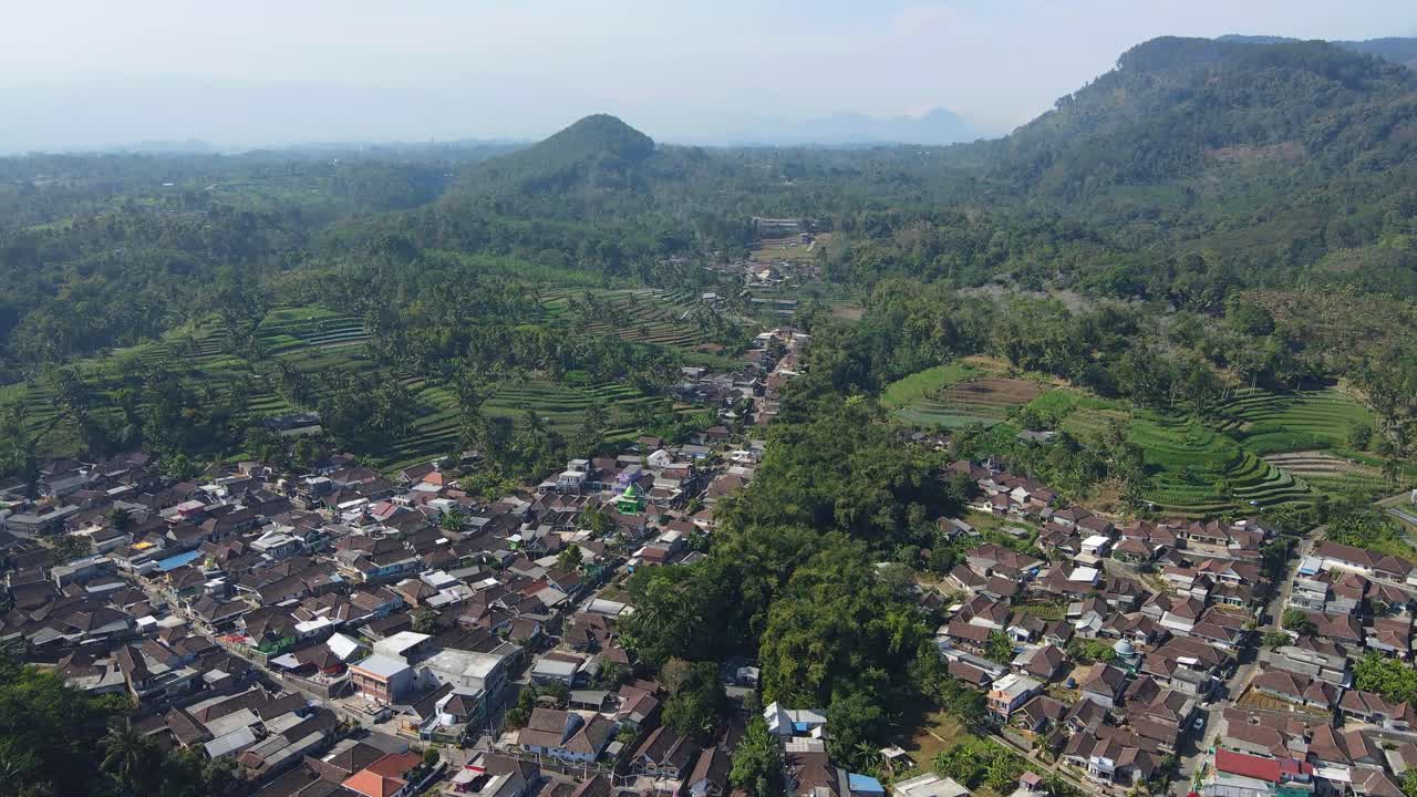 Stunning 4K aerial footage of a peaceful rural landscape with lush green fields and a majestic mountain in the background. Perfect for nature, travel, and documentary projects