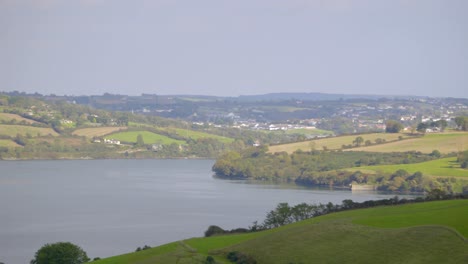 Panoramic-shot-of-green-fields-and-lake