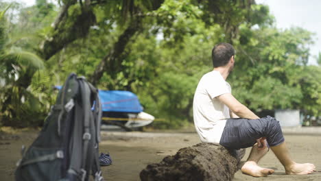 caucasian tourist sitting in trunk wooden tree on sandy beach in costa rica travel holiday paradise destination