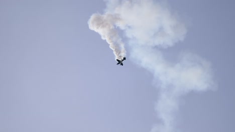 corkscrewing aerobatic airplane spiraling down with smoke trail at airshow