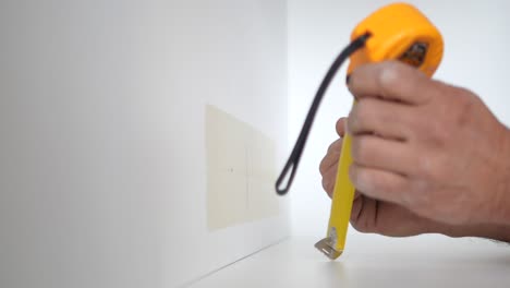 man measuring a wall with a level and pencil