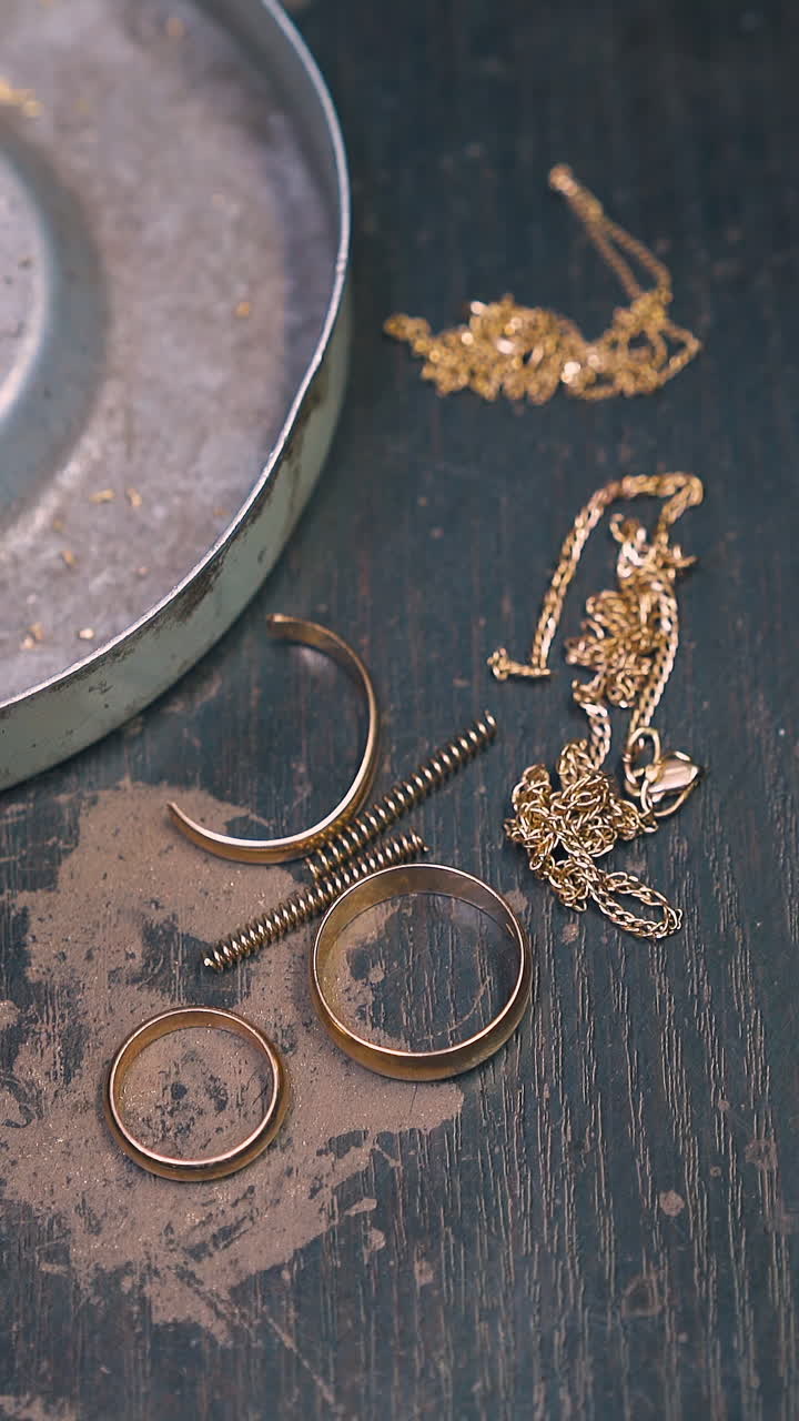 CU: jeweler takes off old rings chains and gold parts from grey box with tweezers on black wooden table close upper view