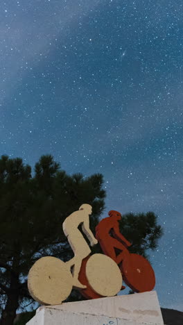 estatua de ciclista y cielo nocturno con estrellas por encima, vista de lapso de tiempo