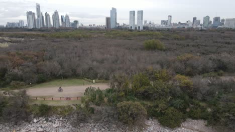 people on bicycle riding on path in front of city skyline in buenos aires at cloudy day