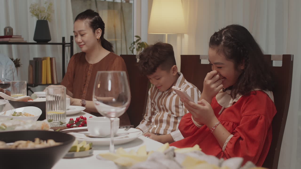Kids Sitting at Dinner Table with Smartphones