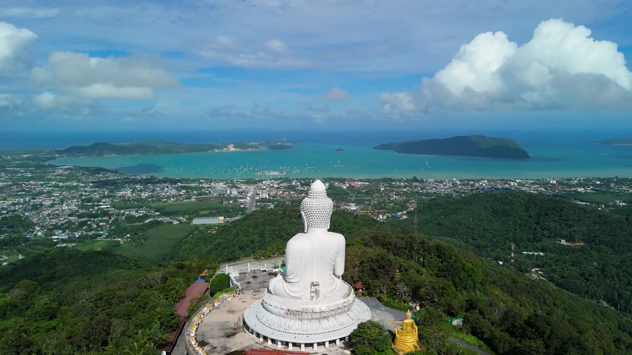 Ripresa aerea inclinata verso l'alto che rivela il Grande Buddha di Phuket sopra la baia di Chalong e le colline costiere