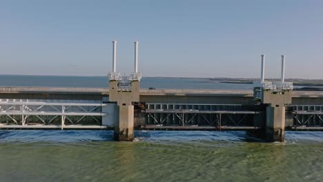 Aerial-shot-tracking-traffic-driving-over-the-Eastern-Scheldt-storm-surge-barrier-in-Zeeland,-the-Netherlands,-on-a-beautiful-sunny-day