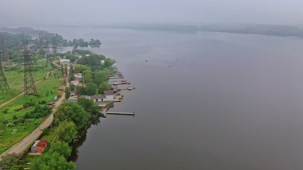 High voltage lines near the river. Electric towers in the countryside on water background. Power transmission lines in nature. Aerial view.