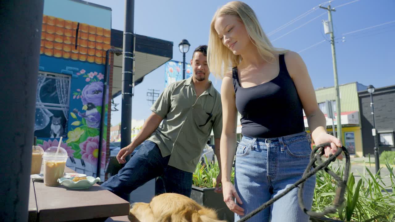 한 부부가 먹기 위해 앉아서 개와 놀고 있다