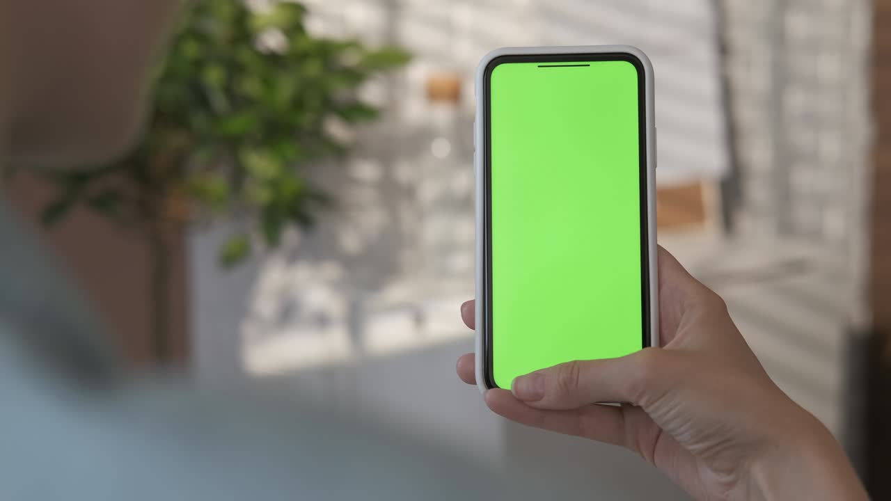 chica usando un teléfono inteligente con pantalla verde en la sala de estar