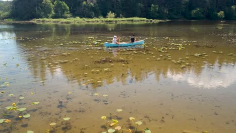 two men canoeing on a lake with lilies