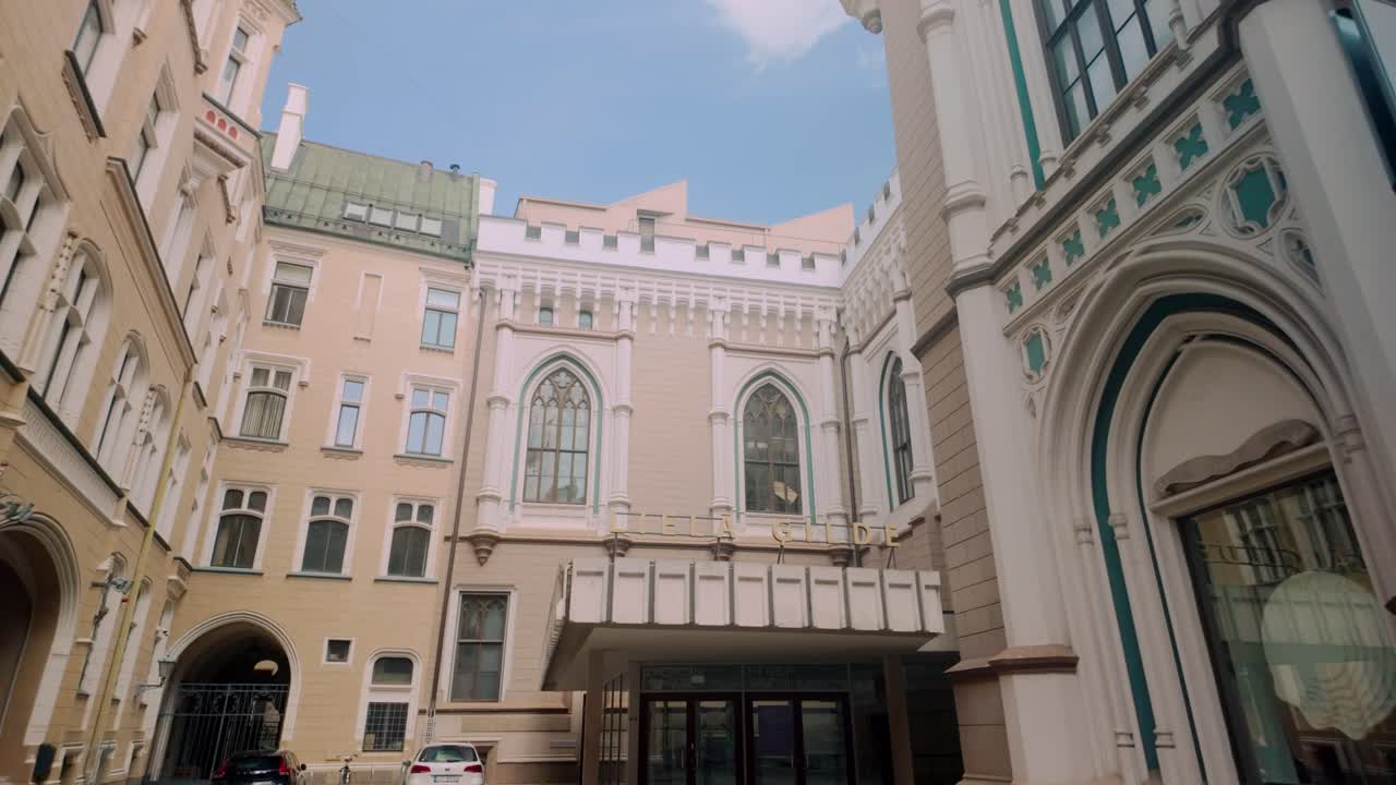 A female tourist takes a photo of the Gothic-style medieval architecture in Riga's old city. The intricate facades and ornate details reflect Riga’s historical heritage. Location: Riga, Latvia