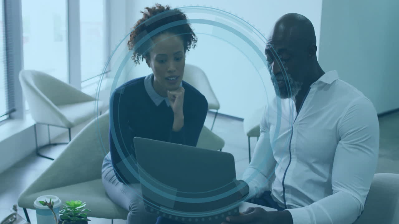 Due persone che discutono di lavoro davanti a un laptop con sovrapposizione animata di interfaccia digitale
