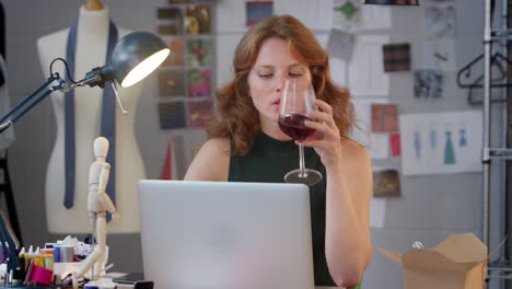 Inhaberin-Eines-Modegeschäfts-Mit-Einem-Glas-Wein,-Die-Spät-Am-Laptop-Im-Studio-Arbeitet