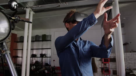 Front-view-of-Caucasian-male-mechanic-using-virtual-reality-headset-in-motorbike-repair-garage-4k