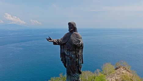 cristo rei of dili statue on top of the hill in timor leste - aerial pullback