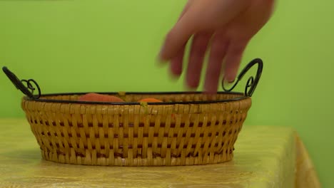 caucasian man's hand taking a tangerine from a basket