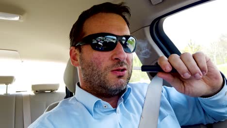 man driving along a highway while using iqos