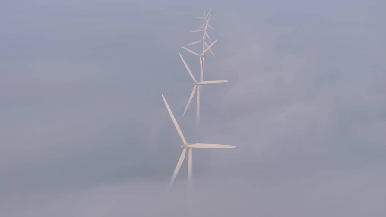 해가 뜨는 동안 낮은 구름과 함께 회전하는 풍력 터빈, 공중