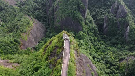 Dramatic-mountain-hike-lookout,-female-hiker-on-Bajiao-Shan-China,-aerial-view