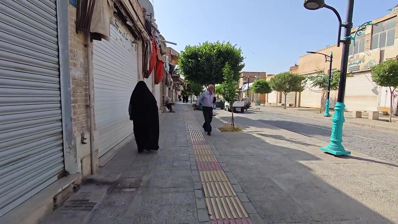 People Walking on a Sunny Sidewalk in a Middle Eastern City