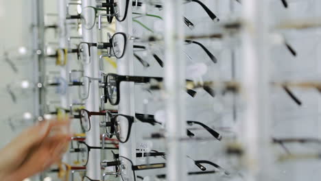 girl choosing glasses. young woman choosing glasses in optician store