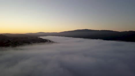 misty mountain valley filled with fog clouds during sunrise with golden gradient sky camera turning right