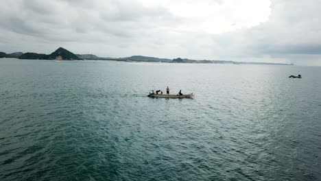 aerial 4k men standing on fishing boat in bay, indonesia