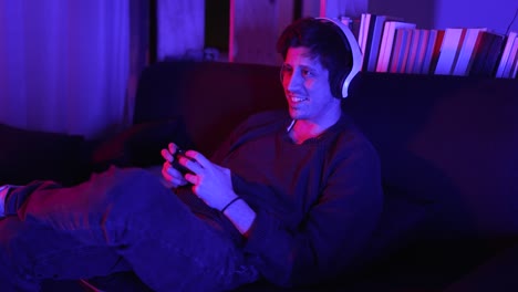 a smiling man in a medium shot plays video games in his apartment
