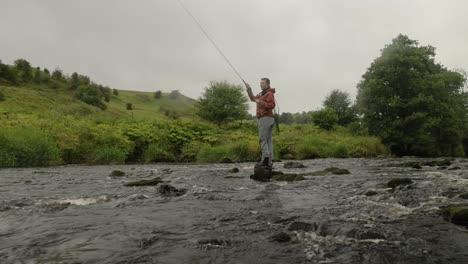 Tiefwinkelaufnahme-Eines-Fischers,-Der-Seine-Fliegen-In-Einen-Kleinen-Bach-Wirft-Und-Versucht,-Fische-Zu-Fangen