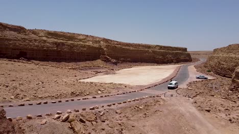 Aerial-forward-drone-shot-of-a-side-way-road-winding-between-the-hills-in-the-middle-of-an-Israeli-desert