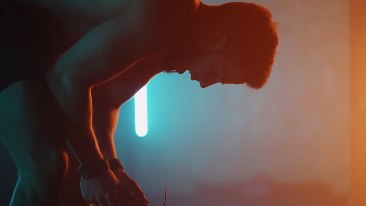 deportista cansado en una sala de gimnasia oscura descansando entre ejercicios deportivos respirando con dificultad