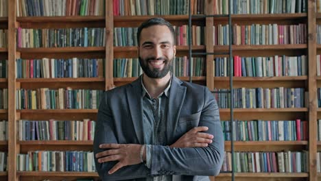 guy is standing in the library. attractive brunette with beard from the middle east.