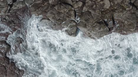 Top-shot-of-a-drone-waves-splashing-on-the-coast-of-an-ocean