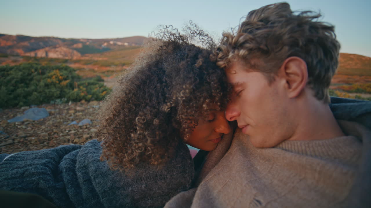 Ethnic lovers resting hills closeup. Romantic couple bonding heads on sunset