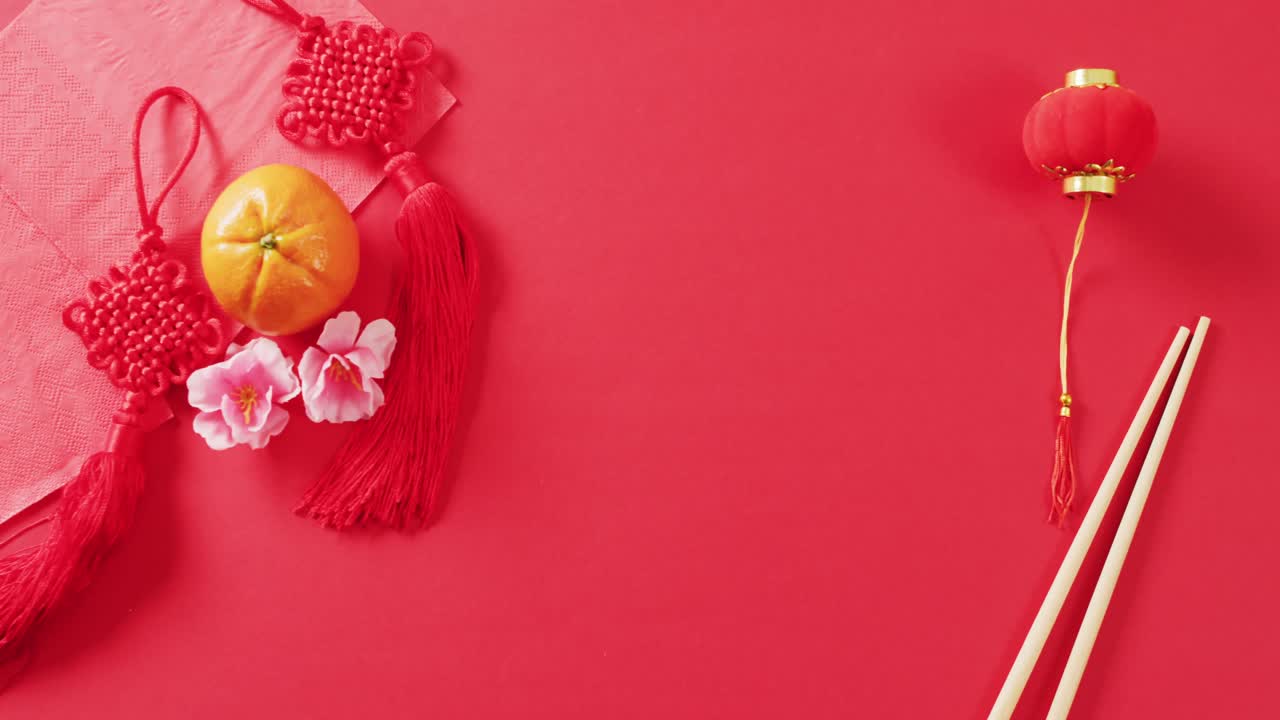 Video of close up of orange and decorations on red background