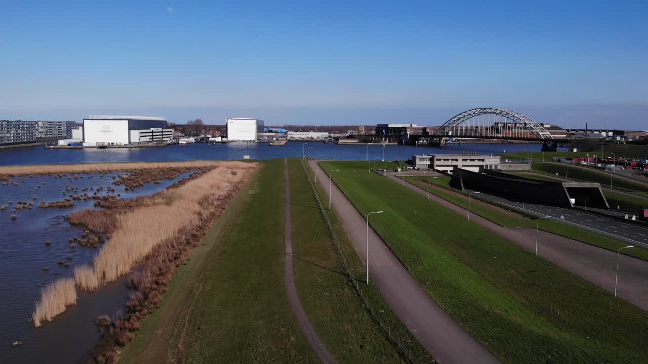 무인 항공기는 네덜란드의 노르트 강을 가로지르는 다리를 볼 수 있는 고속도로에서 자동차와 함께 녹색 잔디 공원 위로 올라갑니다.