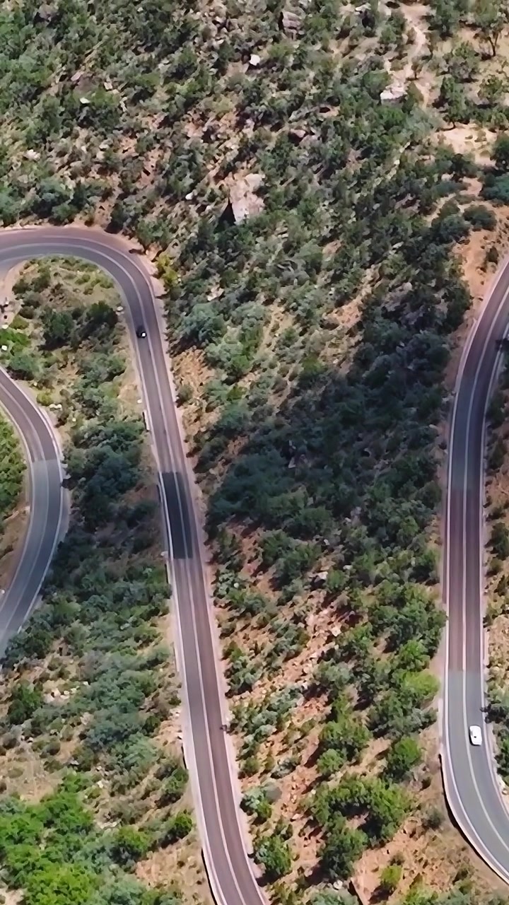 Strada tortuosa nel Mojave, USA, circondata da colline e vegetazione.