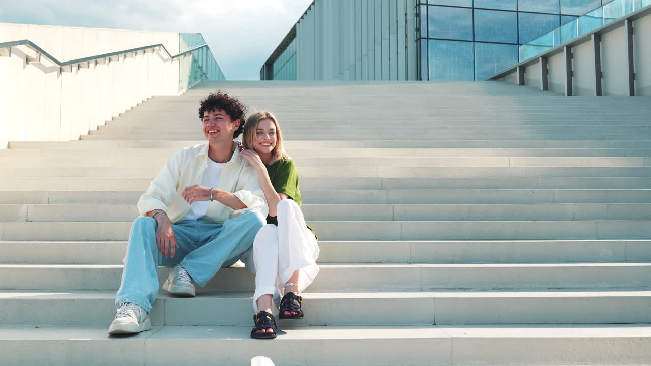 pareja sentada en las escaleras frente a un edificio moderno