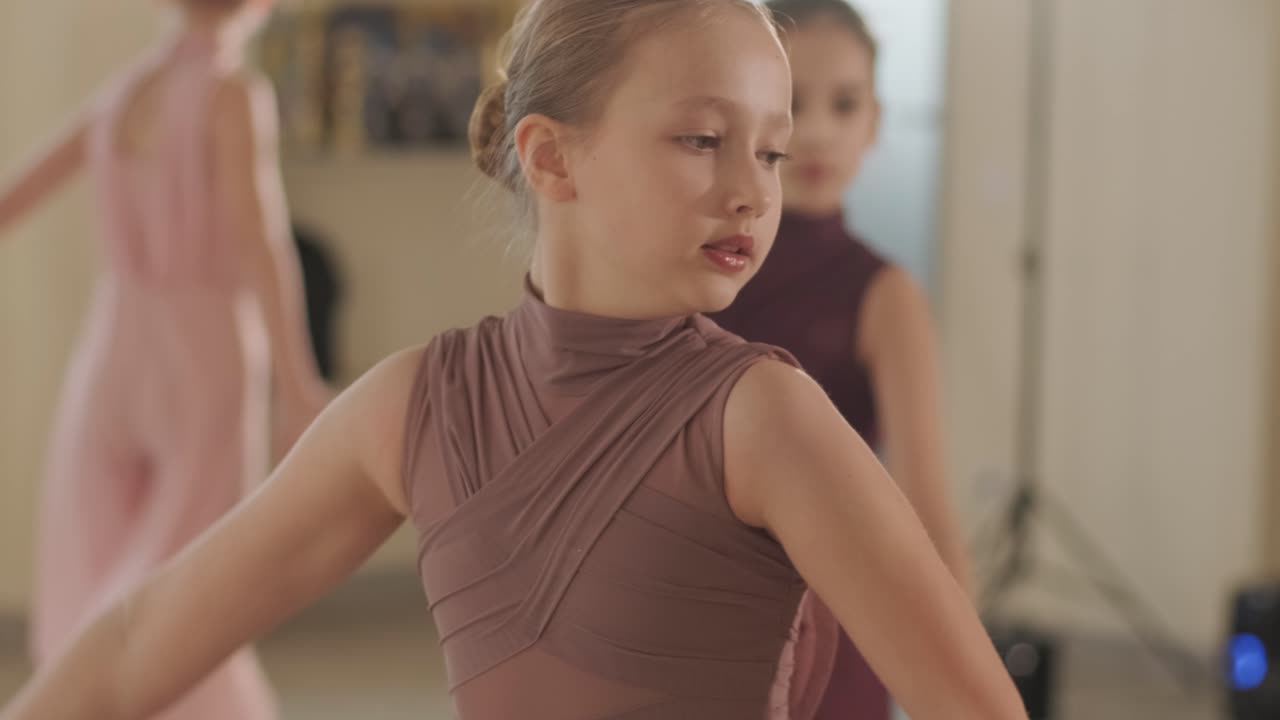 un grupo de jóvenes estudiantes de ballet con ropa de baile negra practicando posiciones en un amplio estudio de ballet con pisos de madera y barras montadas en la pared. expresiones enfocadas y movimientos sincronizados.